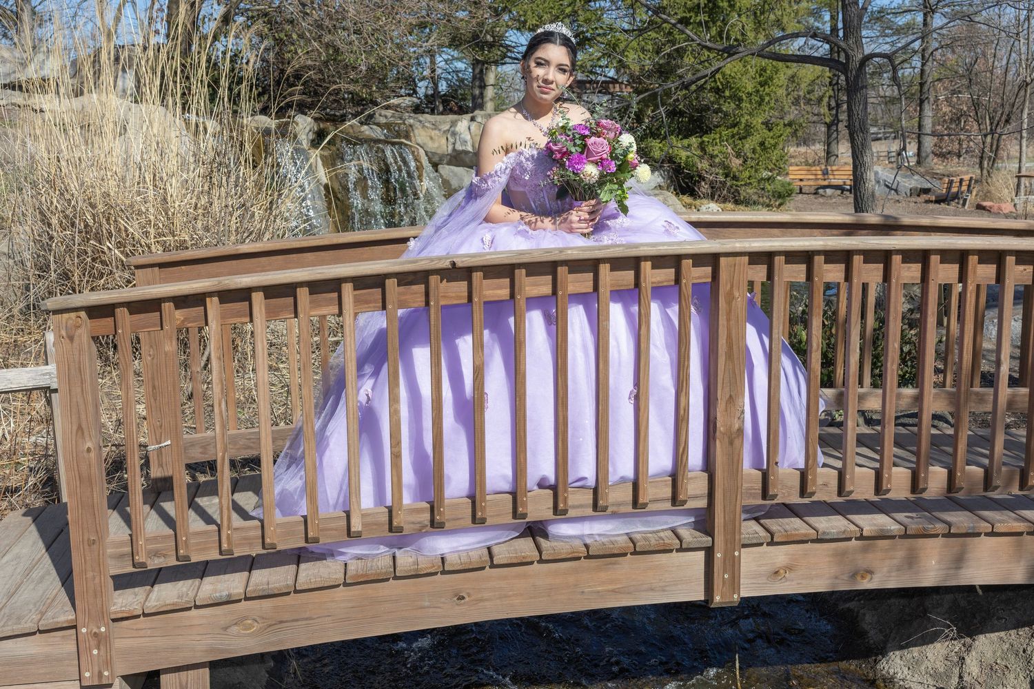 A wooden bridge in a park decorated with pink and purple ribbons and flowers for a springtime celebration.