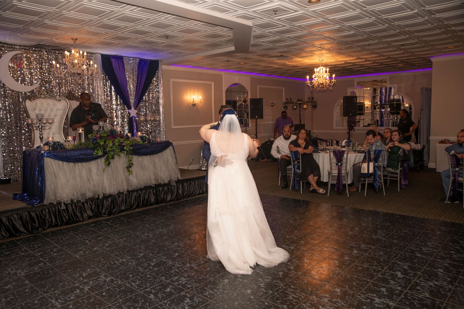 Wedding reception dance floor illuminated with purple lighting and elegant decor in a grand ballroom.