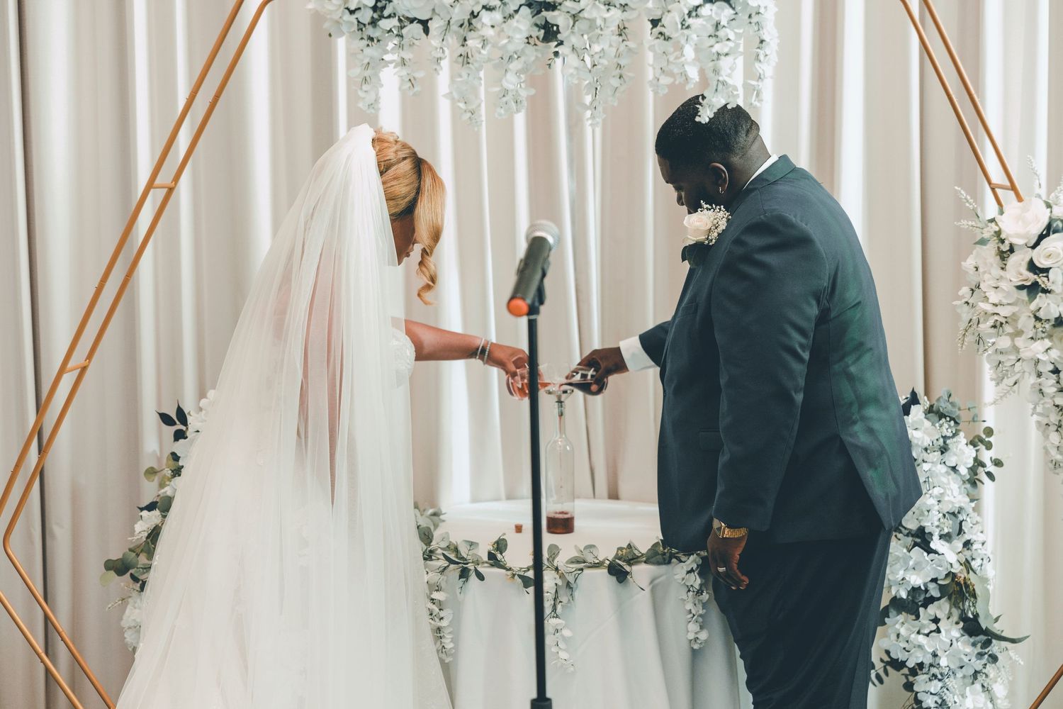 A couple exchanges vows under a floral arch during an intimate wedding ceremony.