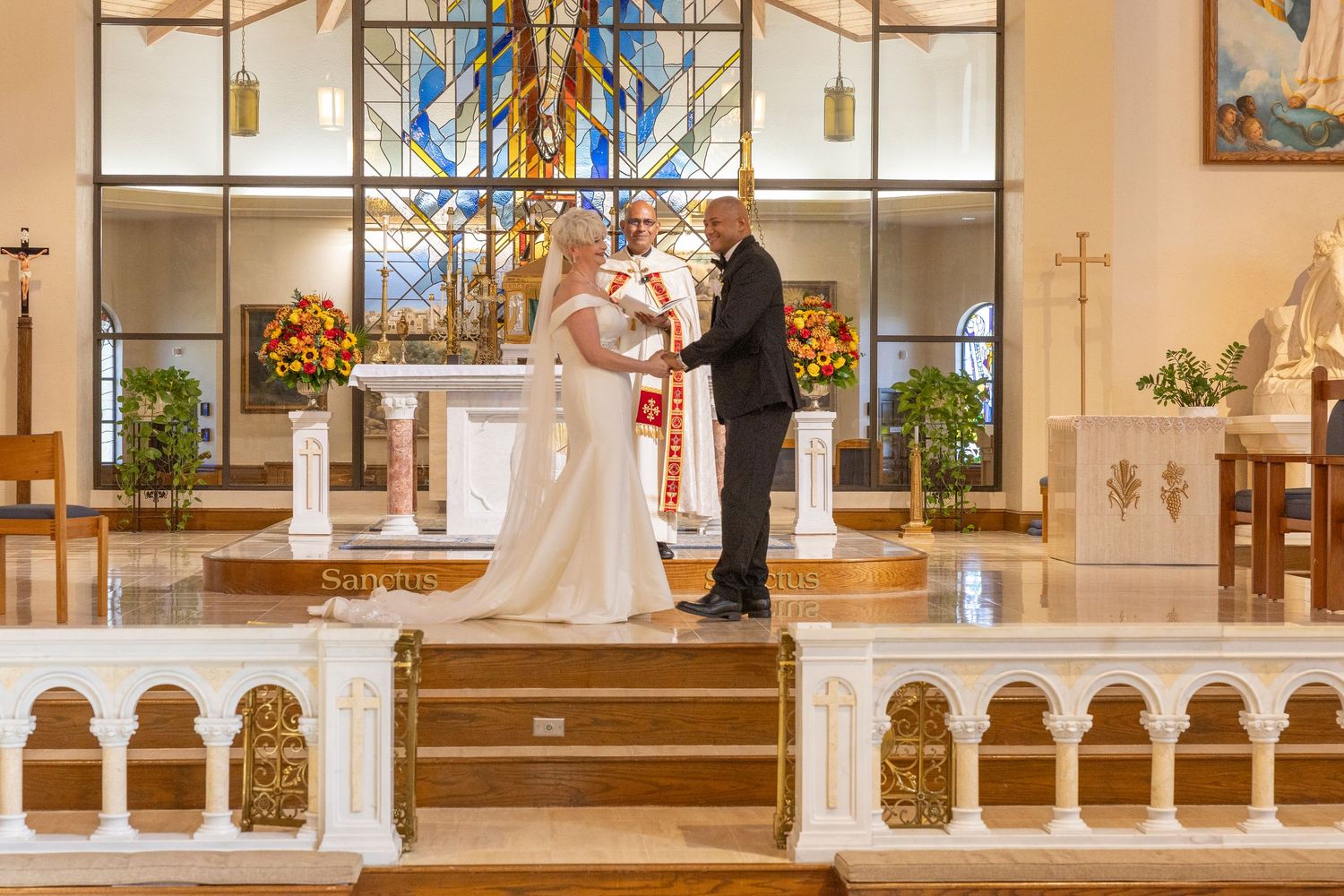 A wedding ceremony takes place in a bright, modern church with white columns and large windows.