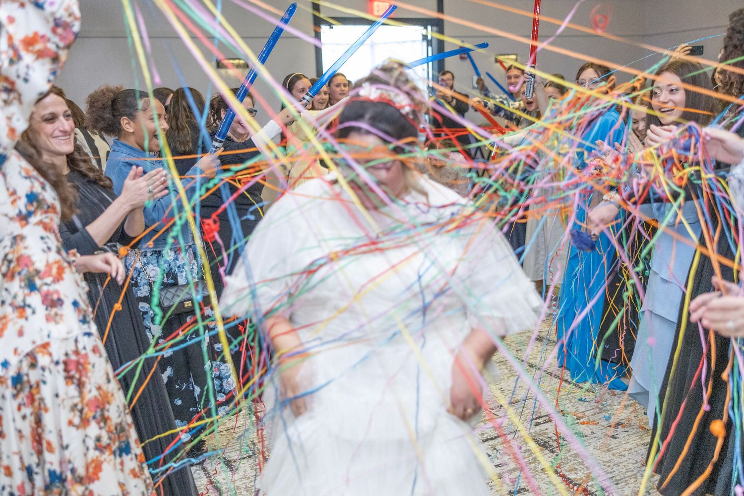Wedding guests celebrate with colorful streamers and confetti during an outdoor celebration ceremony.