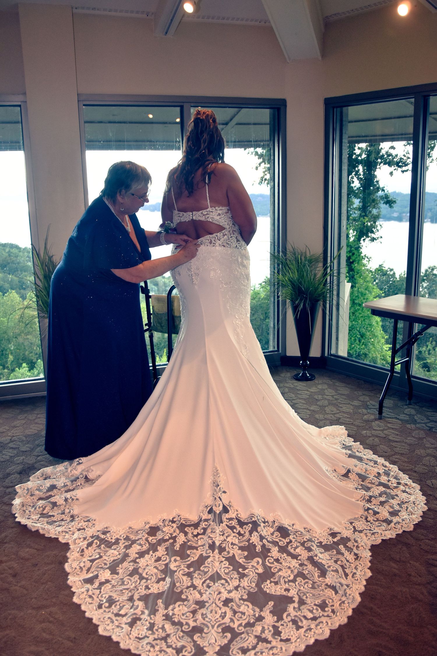 A couple shares a romantic moment in their wedding attire with a stunning lace train on the bride's dress.
