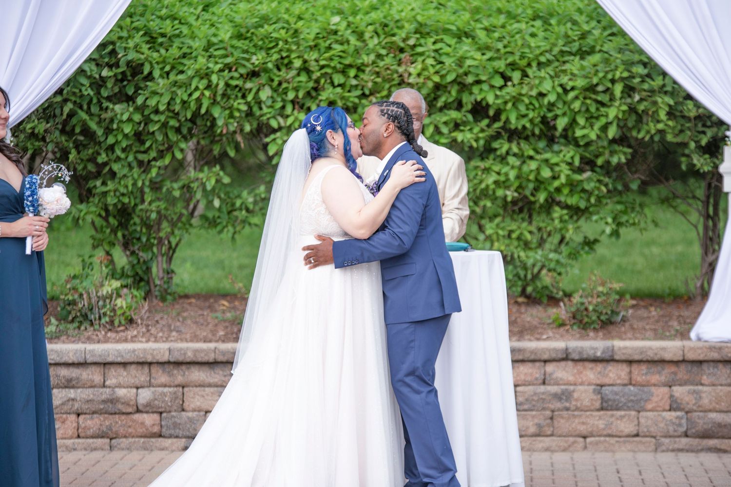 A wedding couple shares an intimate moment under white draping in an outdoor garden setting.