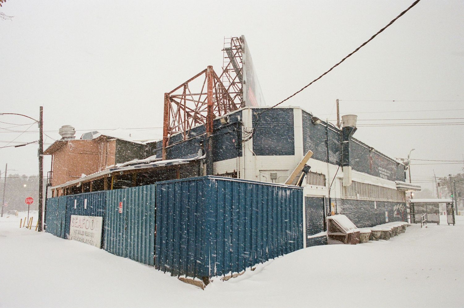 Snow-covered industrial building with shipping containers and metal framework in winter.
