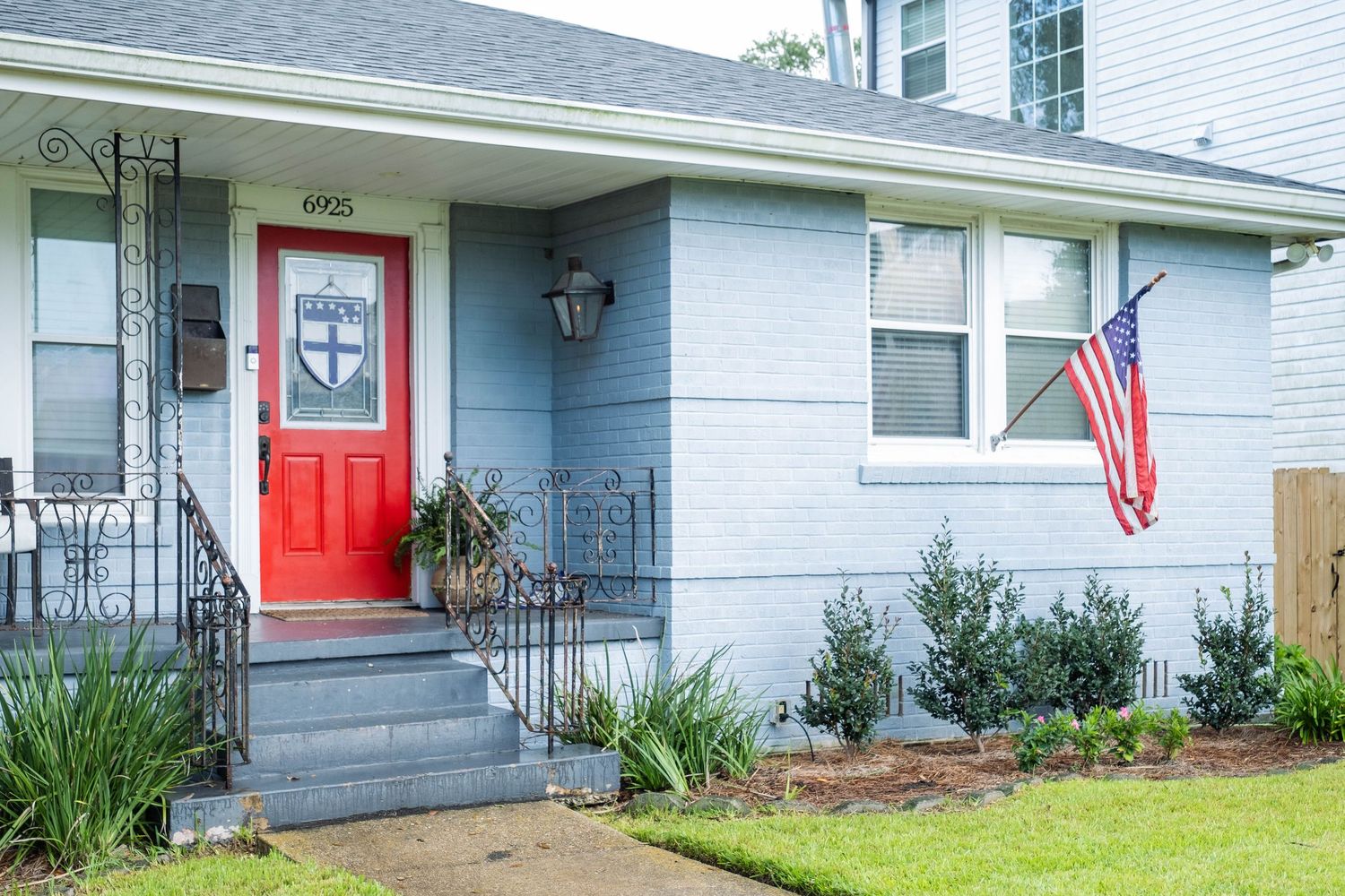 Row of white residential houses with red and blue doors along a suburban street.