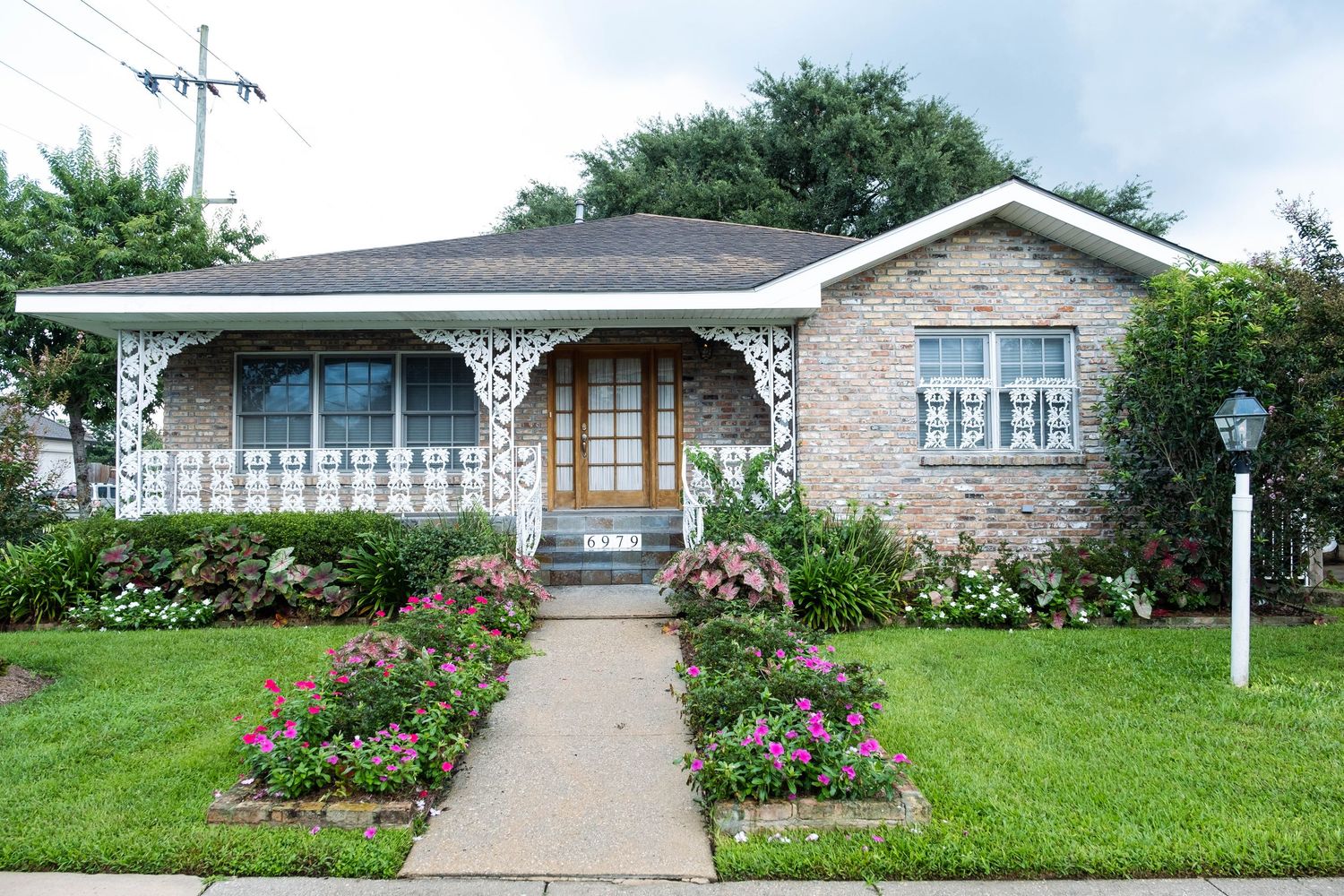 Ranch style brick house with covered porch and landscaped front yard on a sunny day.