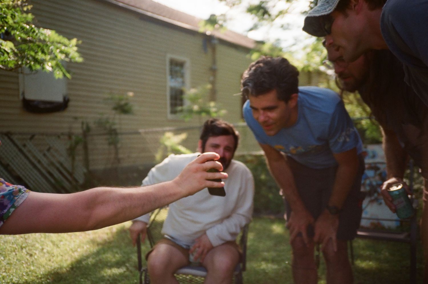 Group of people relaxing in a backyard on a summer day.