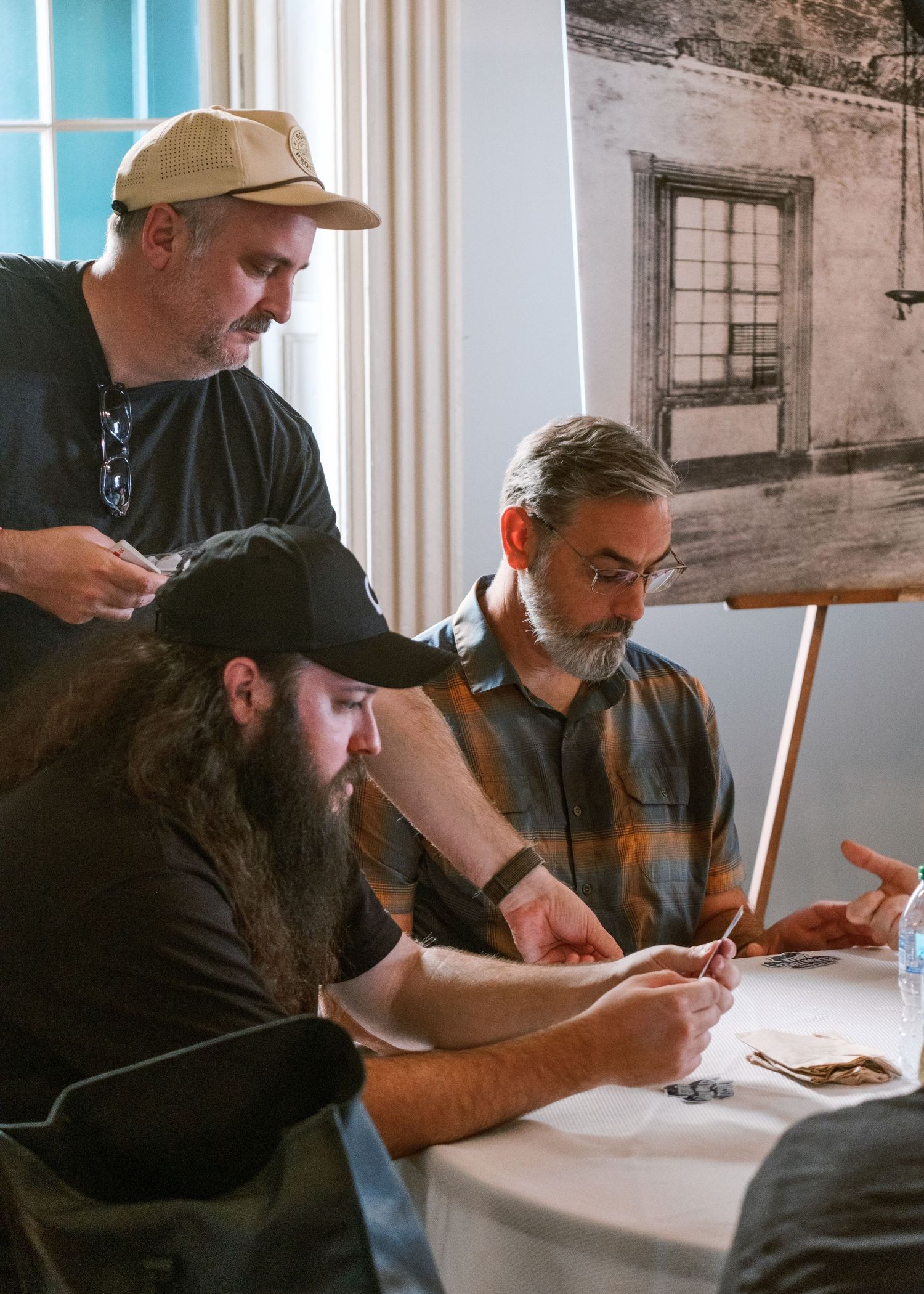 Group of people seated at a white table writing or working together indoors.