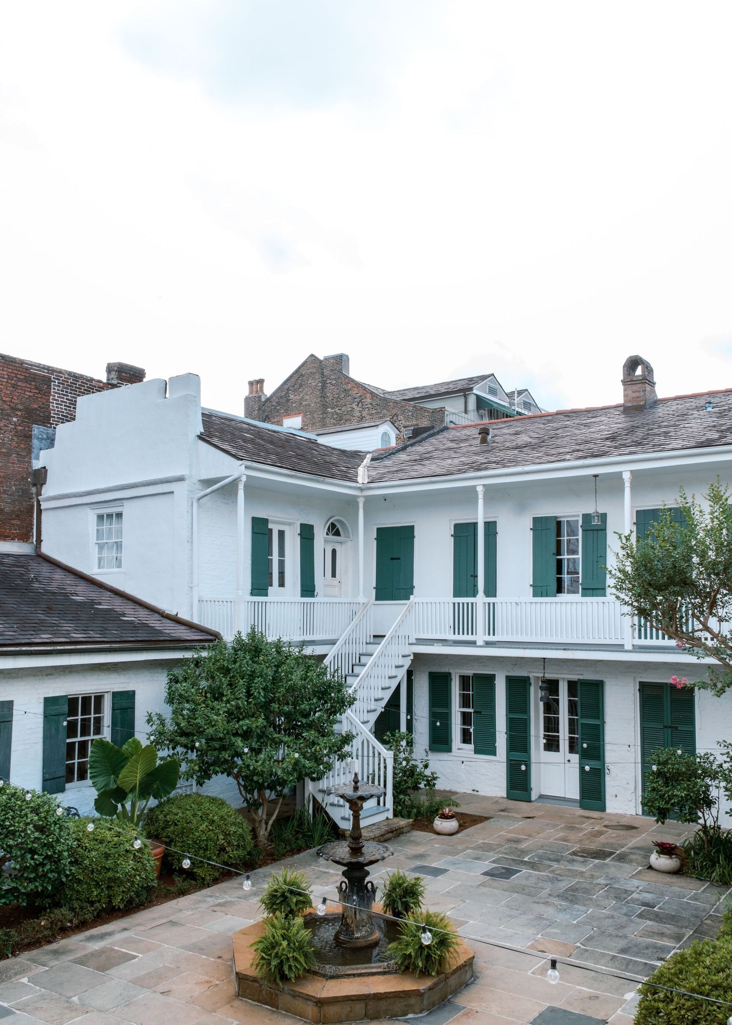 White colonial-style building with green shutters and wraparound porch in historic district.