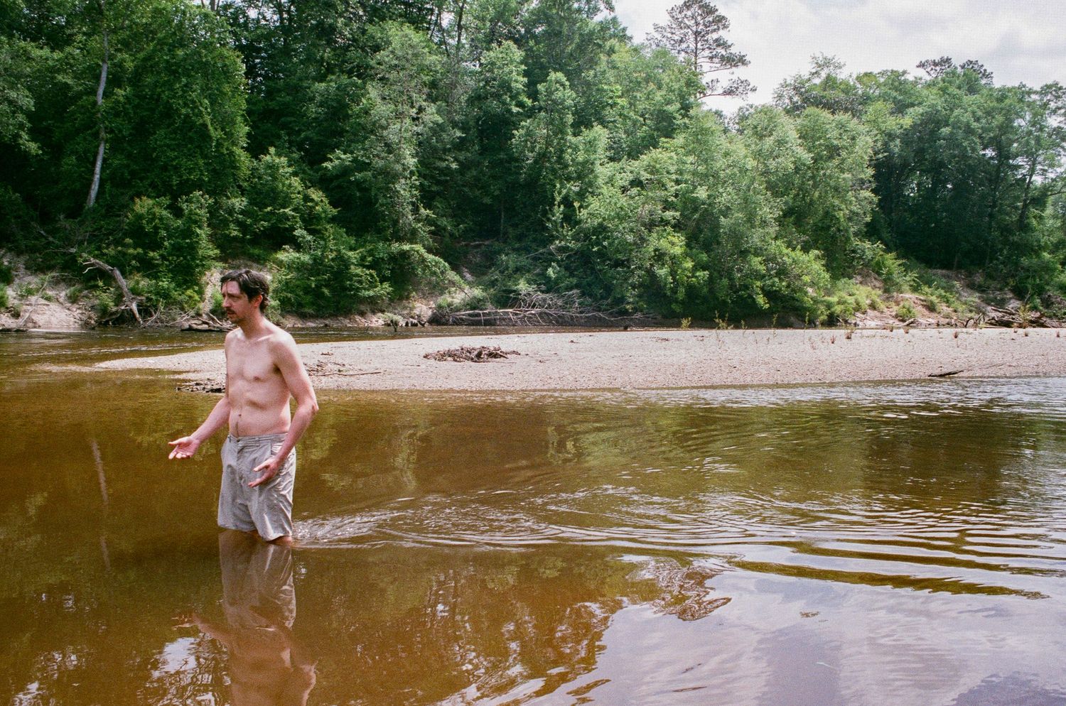 People splashing and playing in a shallow river on a sunny summer day.