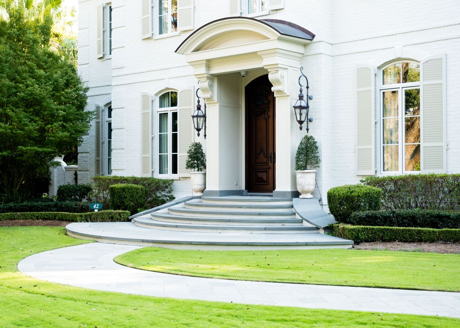 Elegant white mansion with classical architecture and manicured lawn.