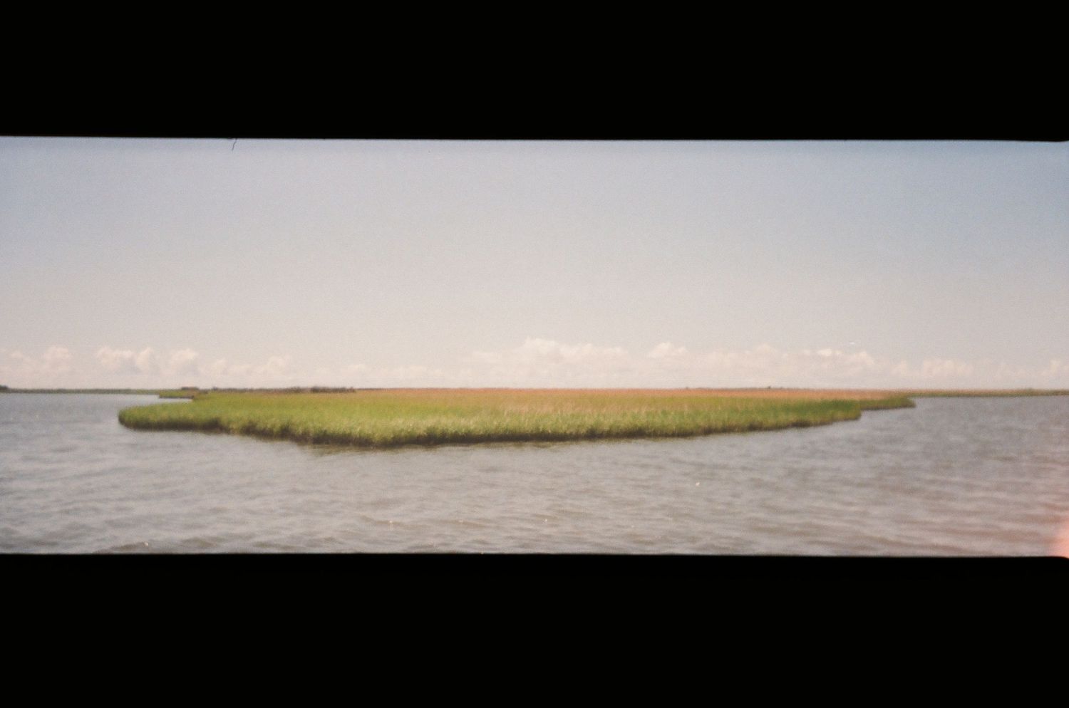 Panoramic view of a marsh island surrounded by calm waters.
