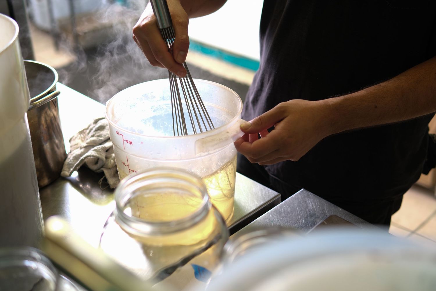Hands preparing food ingredients on a stainless steel kitchen counter.