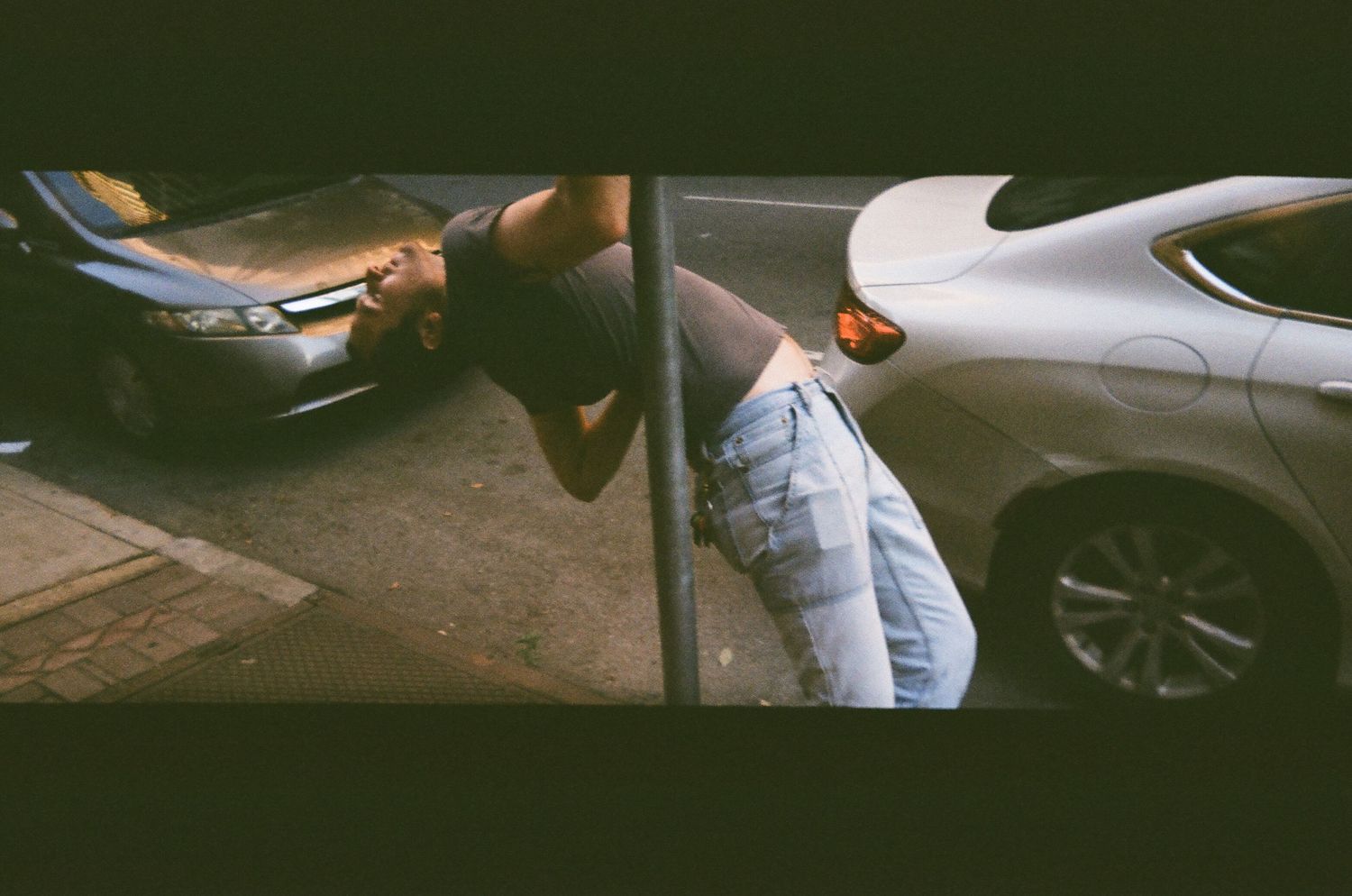 Artistic photo of cars and someone leaning against a vehicle in an urban setting.