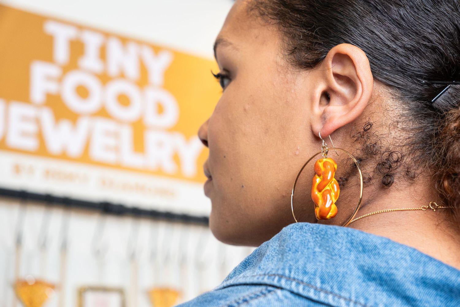 Side view of statement earrings and denim jacket in outdoor setting.