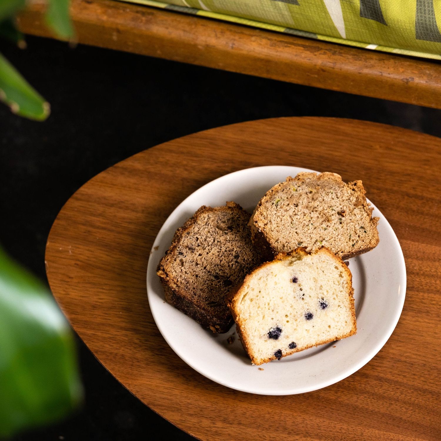 Slices of freshly baked raisin bread arranged on white plates against a dark wooden surface.