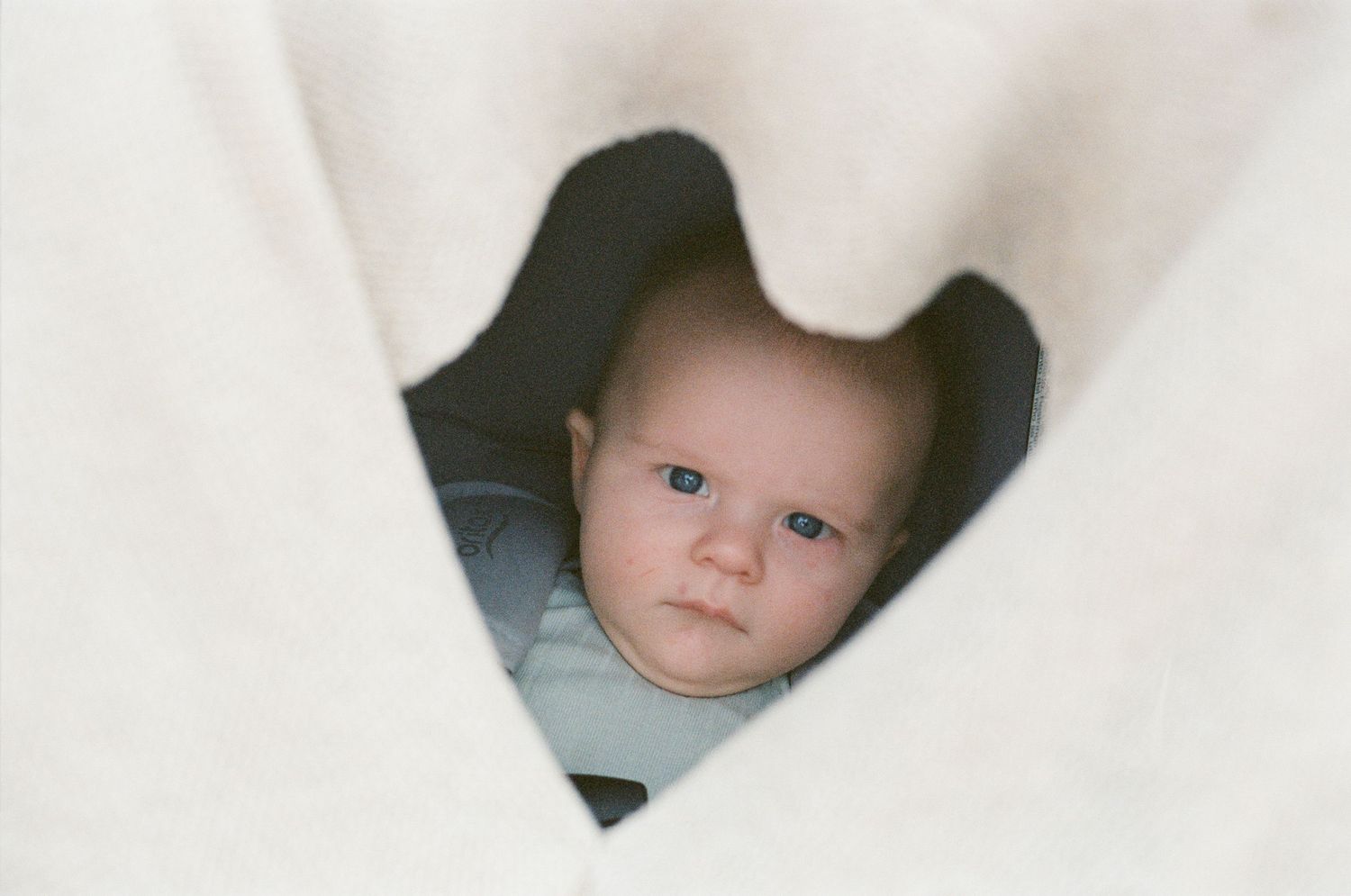 Close-up view of a baby's face peeking through white fabric.