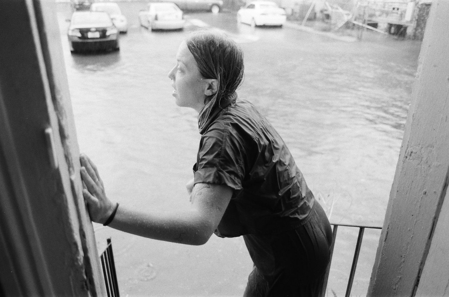 Black and white photo of someone looking out from a doorway during a flood.