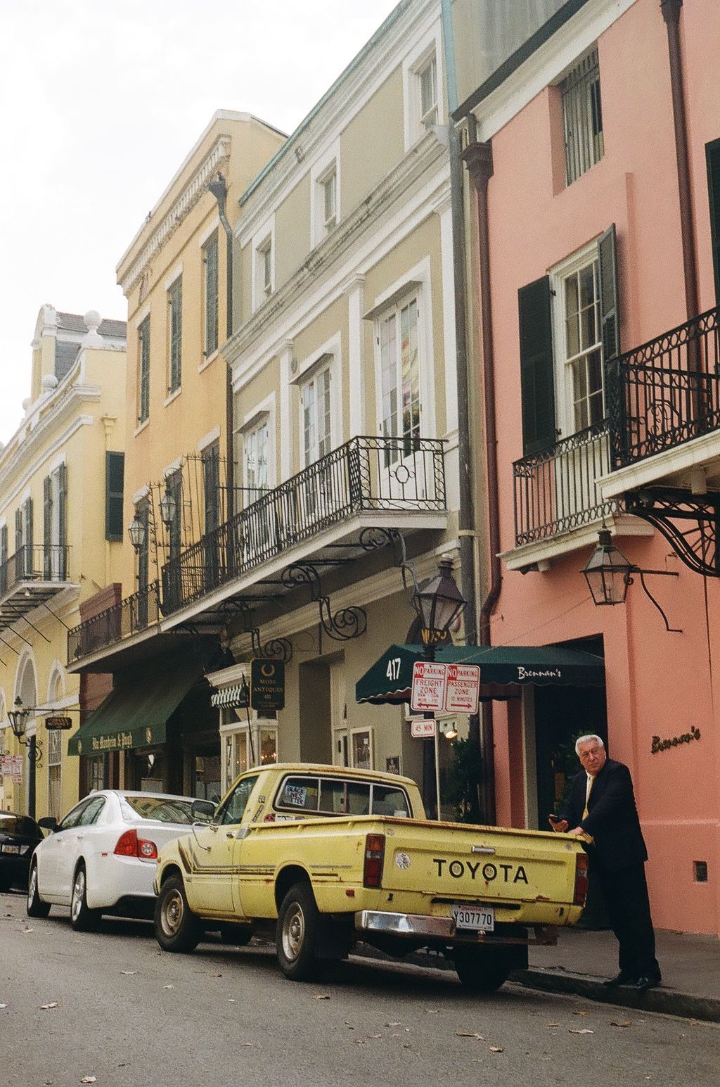 Colorful row of historic buildings with parked cars along a French Quarter street.