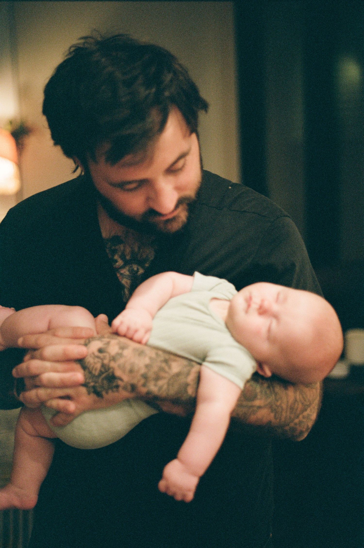 Tender moment between parent and infant in dim lighting.