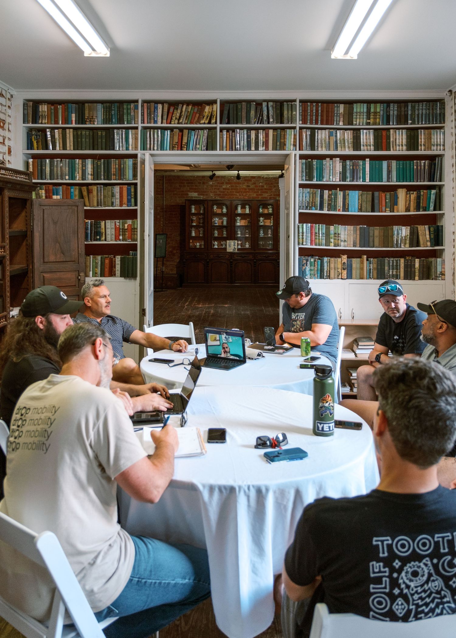 Study room with bookshelves and people working at white-clothed tables.