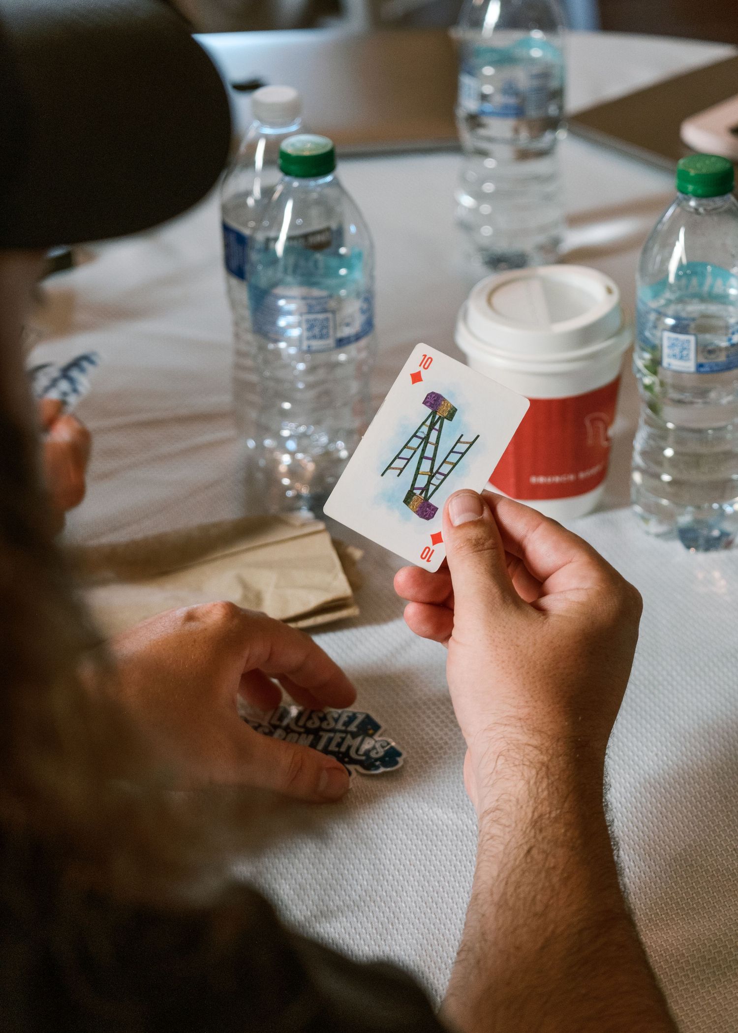 Close-up of hands holding and examining small white cards on a table.