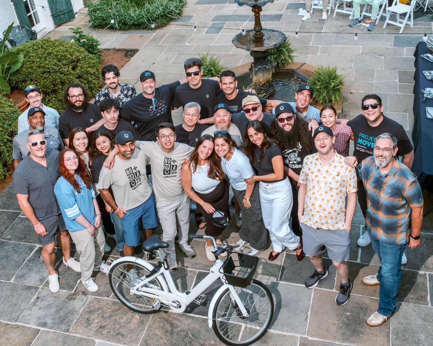 Casual group photo of people gathered outdoors with a white bicycle.