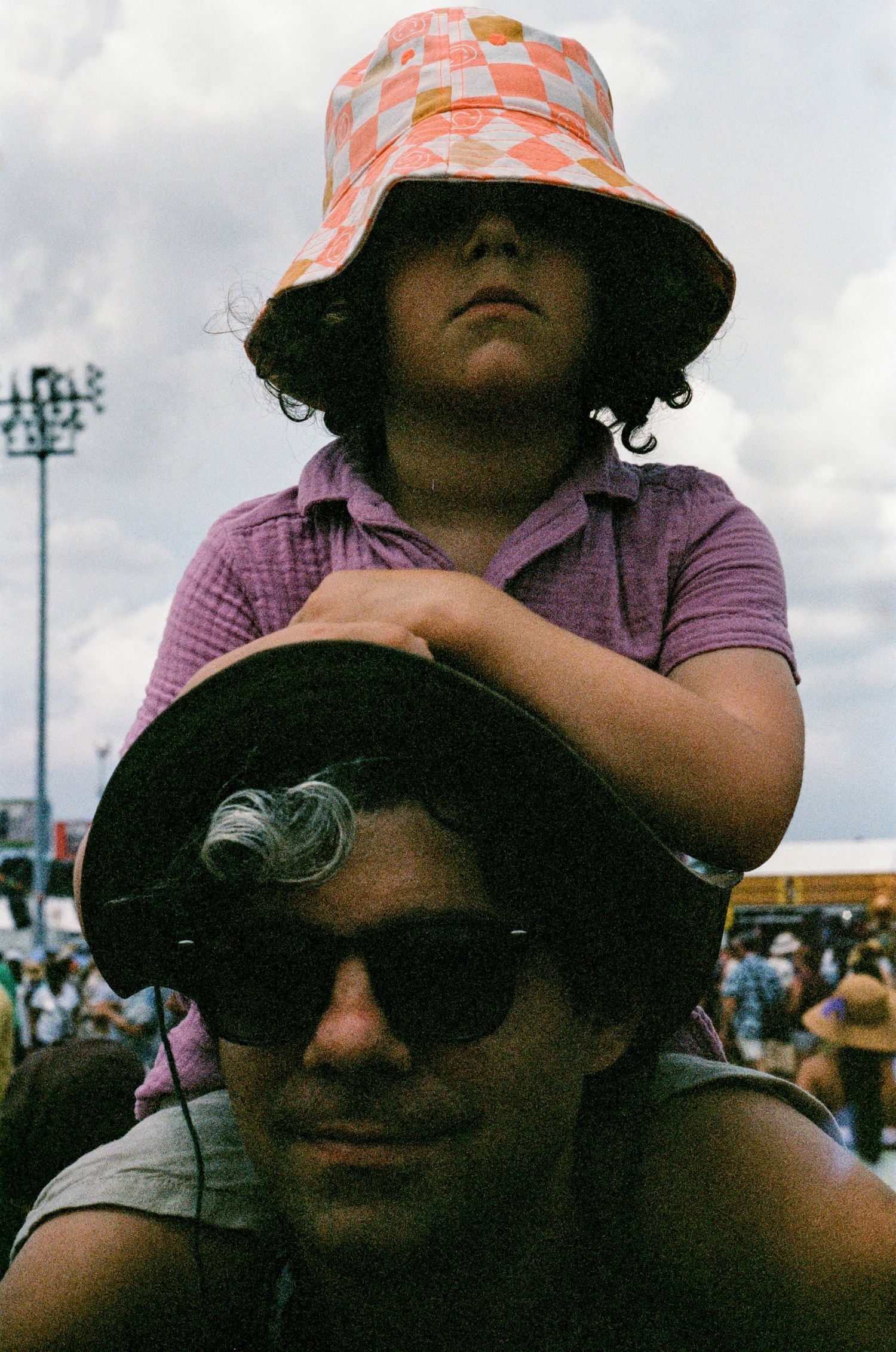 People wearing sunglasses and floral hats at an outdoor event.