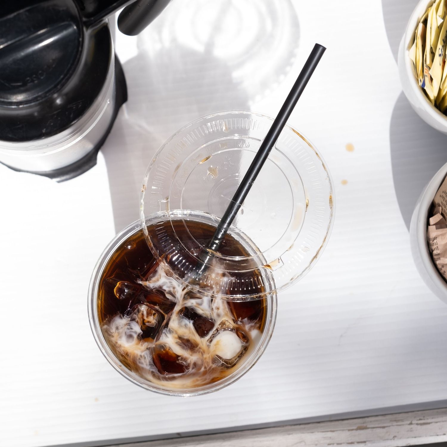 Iced coffee being stirred in a clear glass with ice cubes visible.