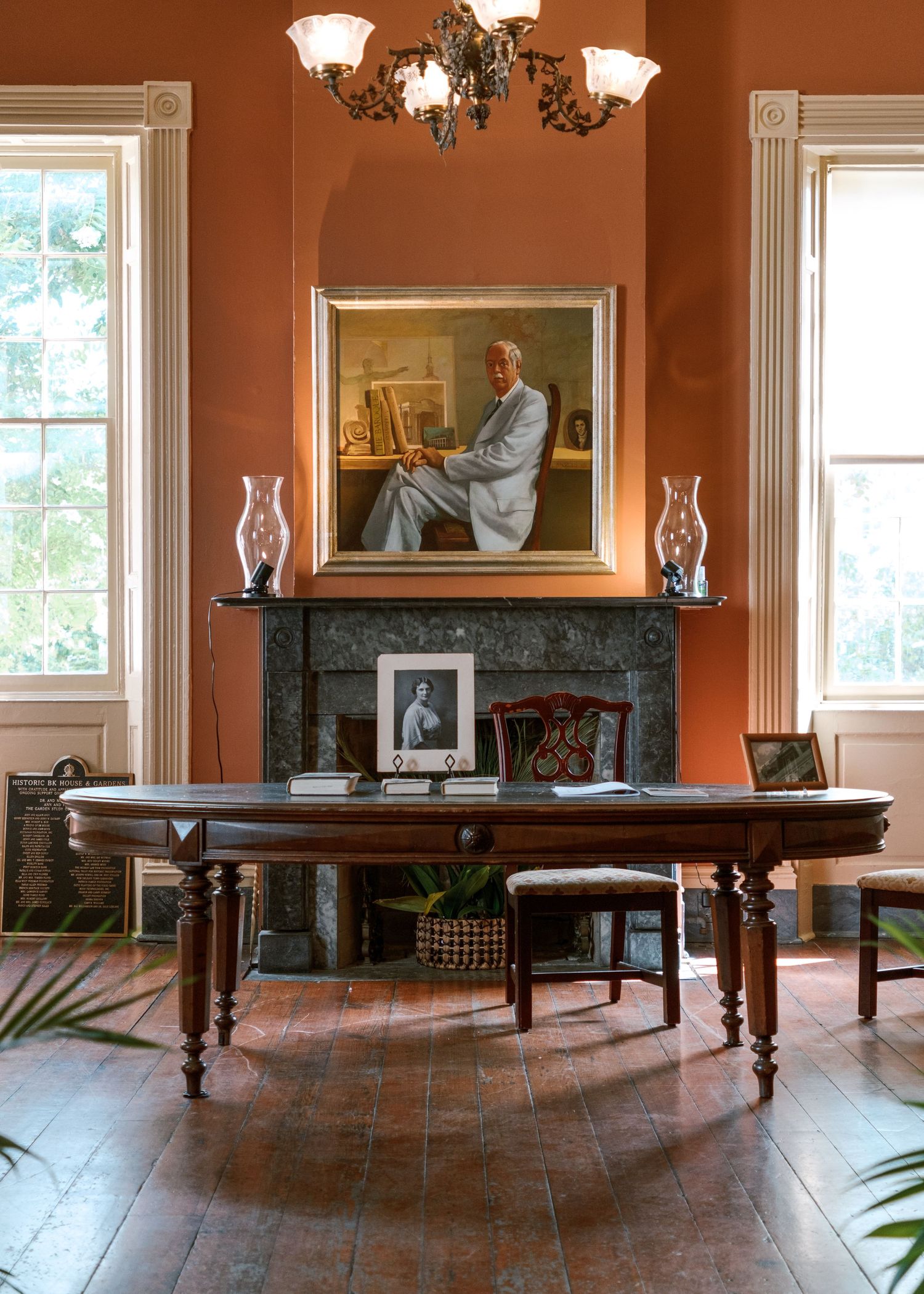 Elegant historic room with orange walls, ornate chandelier, and antique wooden furniture.