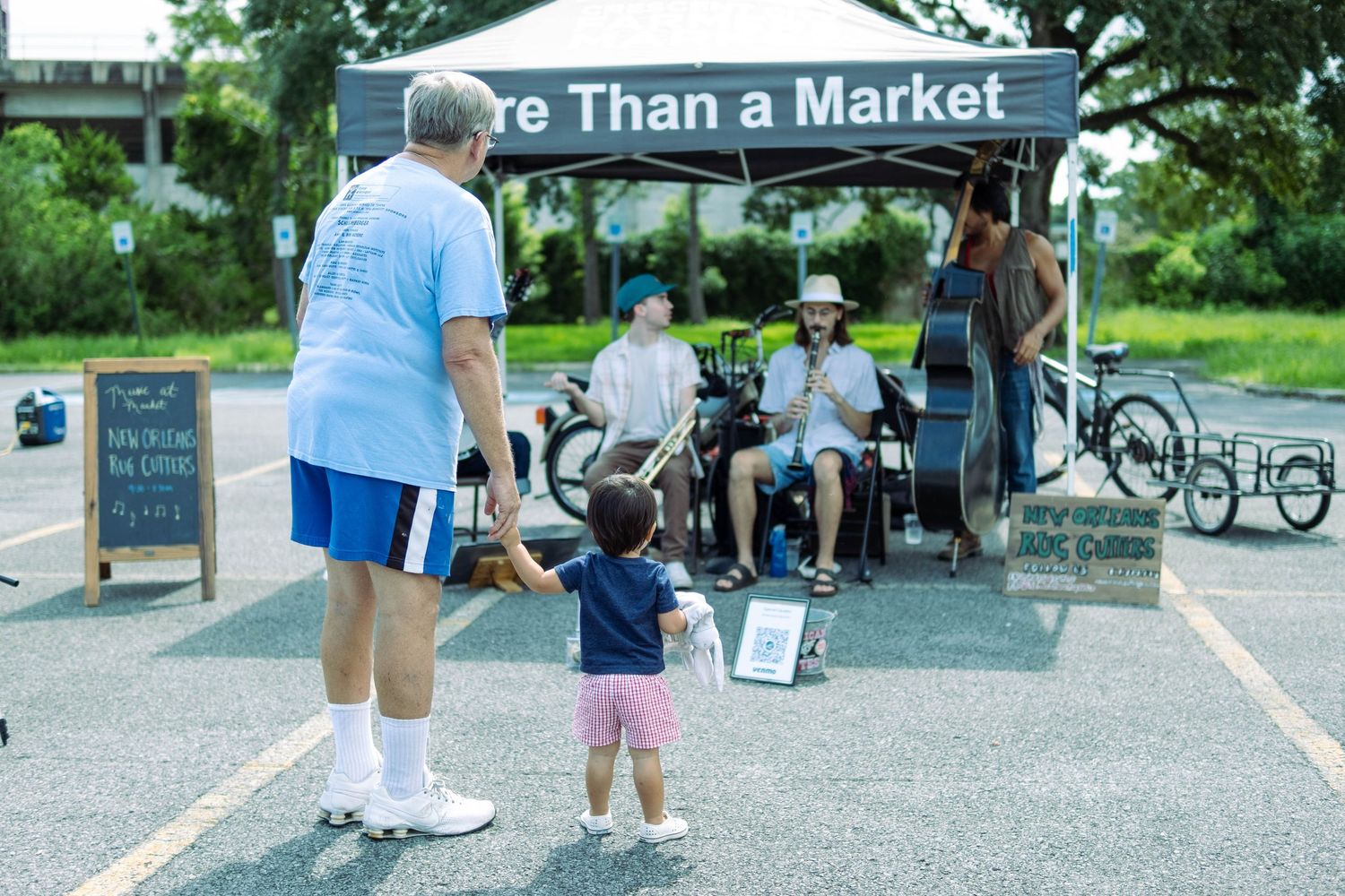 Outdoor market stalls with vendors and shoppers under canopy tents.