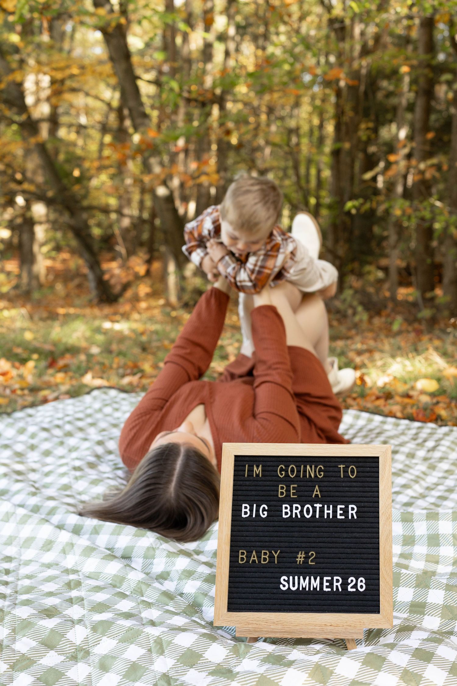 A series of pregnancy announcement photos on a checkered blanket with letter boards revealing a summer due date.