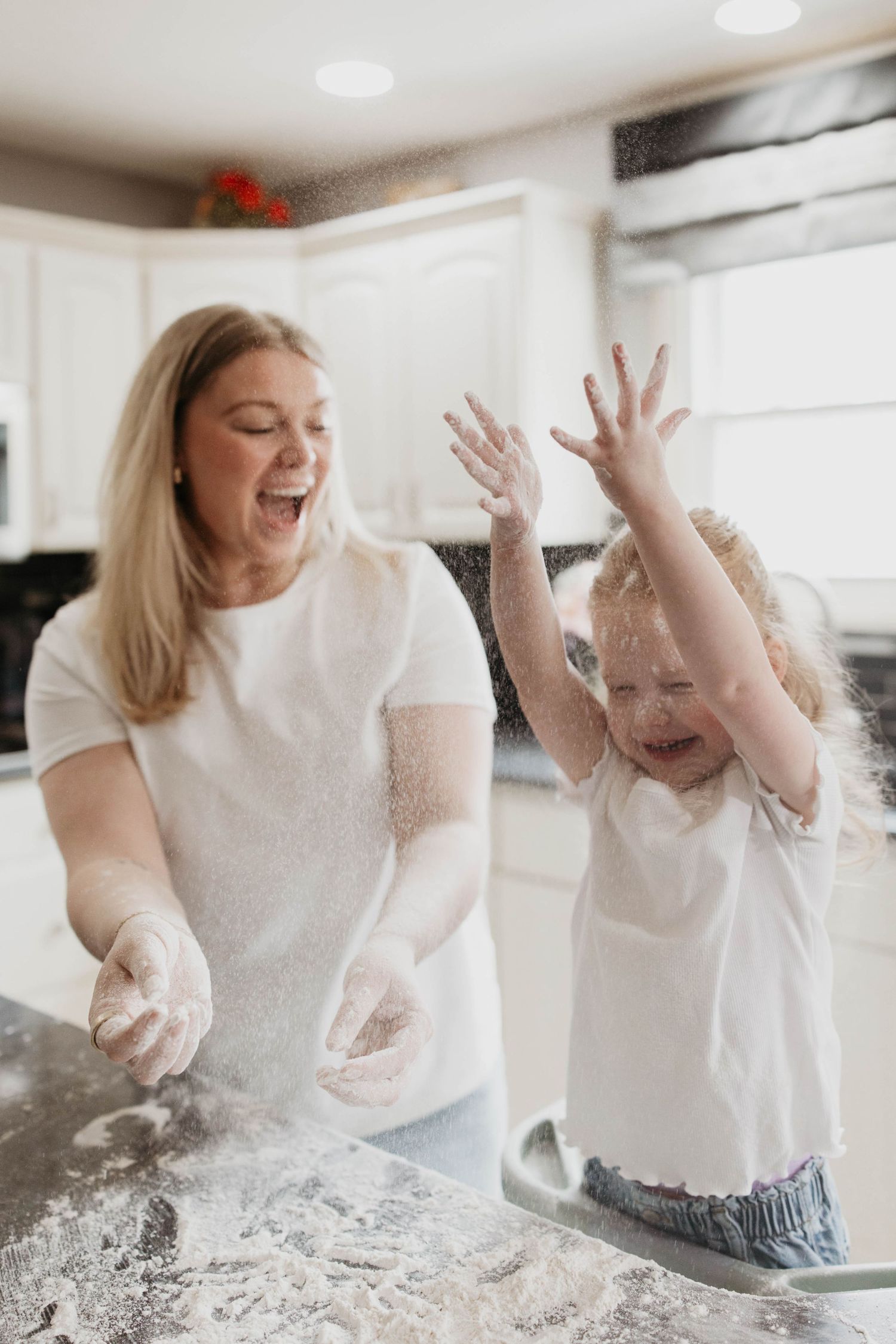 Mother and child playing together in kitchen with flour making a joyful mess while baking.