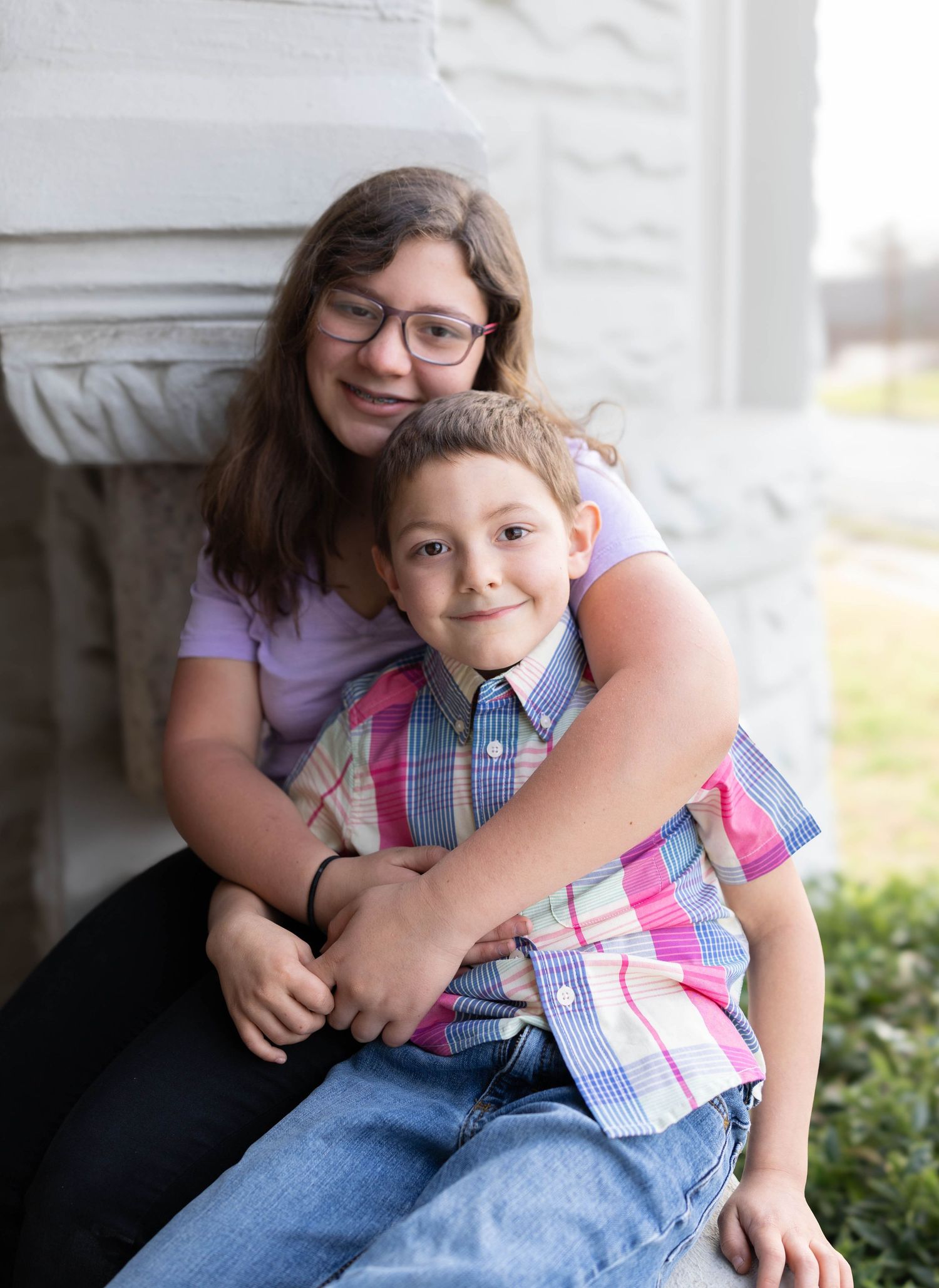 Two people sit together and share a warm embrace while sitting on outdoor steps.