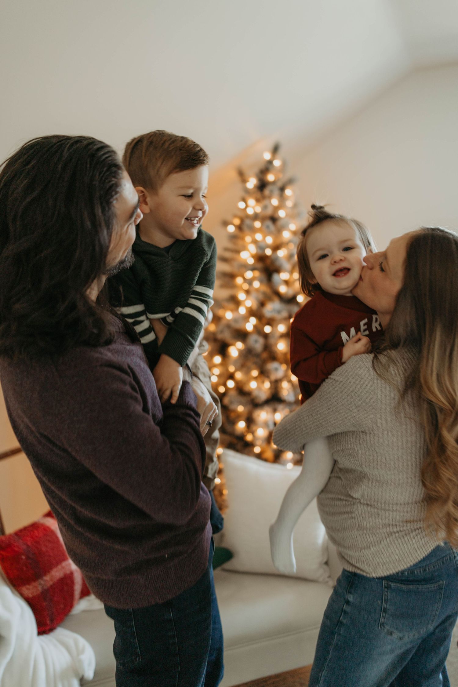 Family sharing joyful moment together in living room with Christmas tree glowing in background.