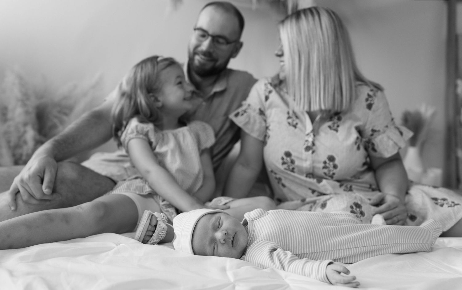 A collage of monochrome photos showing intimate moments between a baby and parents during everyday activities.
