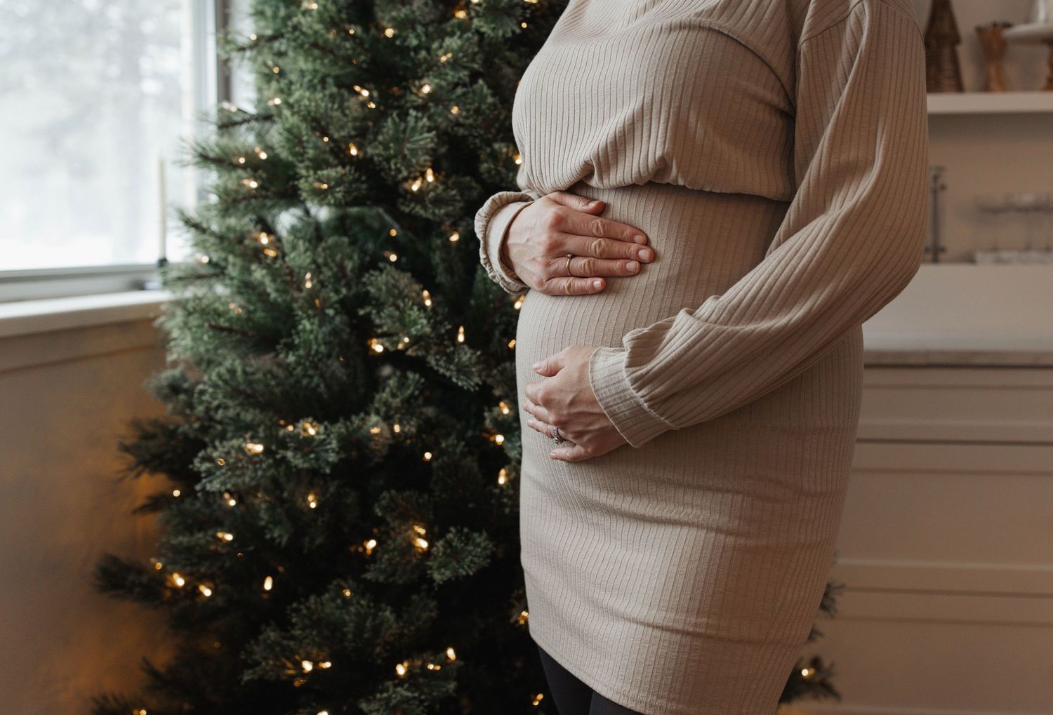 Collage of maternity photos showing a pregnant person in a cream sweater against a Christmas tree backdrop.