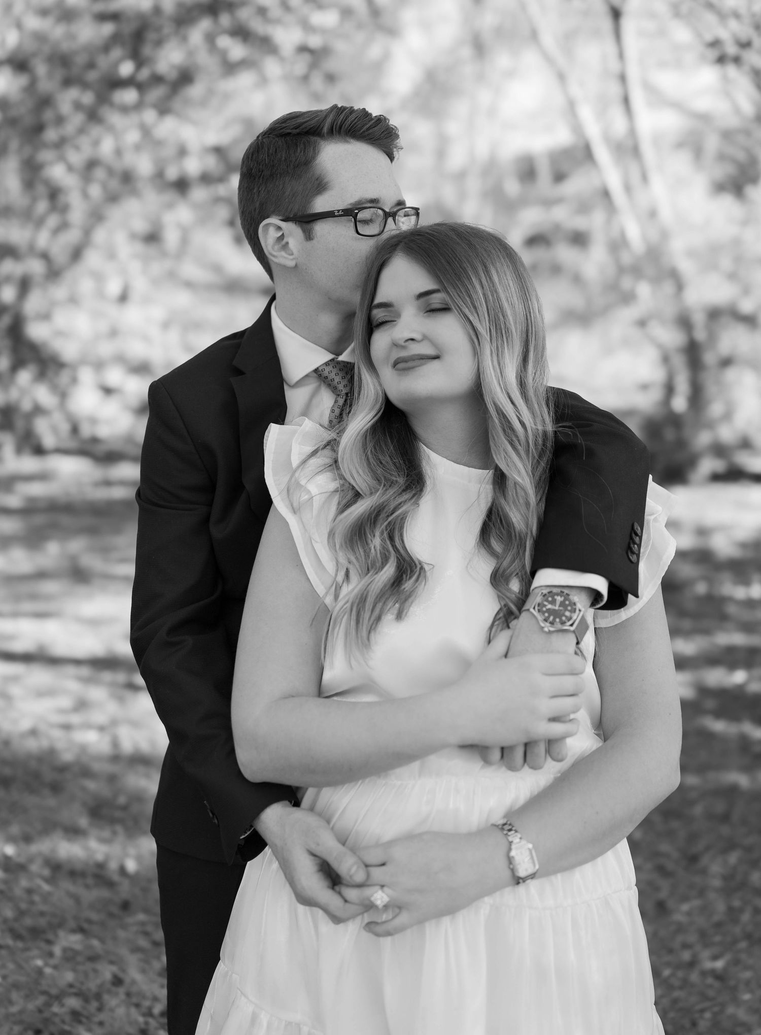 Black and white romantic portrait of a couple embracing outdoors, sharing an intimate moment in a natural setting.