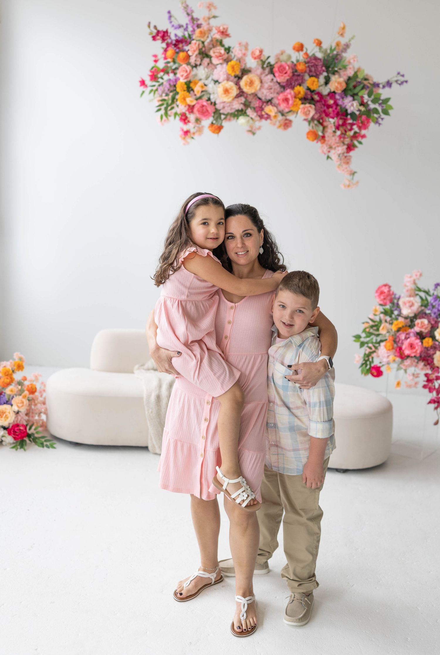 Beautiful floral arrangement in pink and coral tones decorates a bright studio setting with white curved sofa and decor.