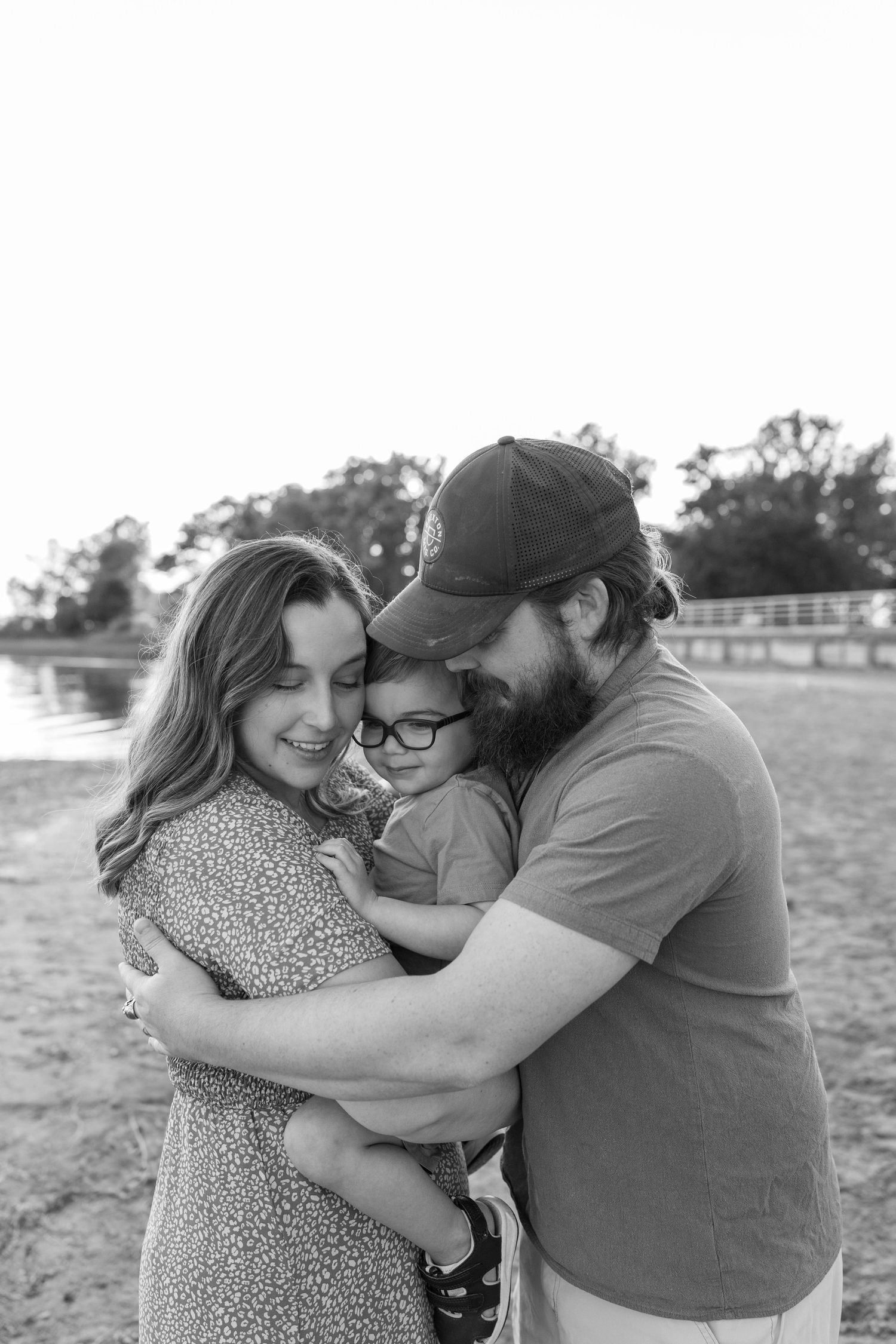 A family hugs together on a sandy beach during sunset.