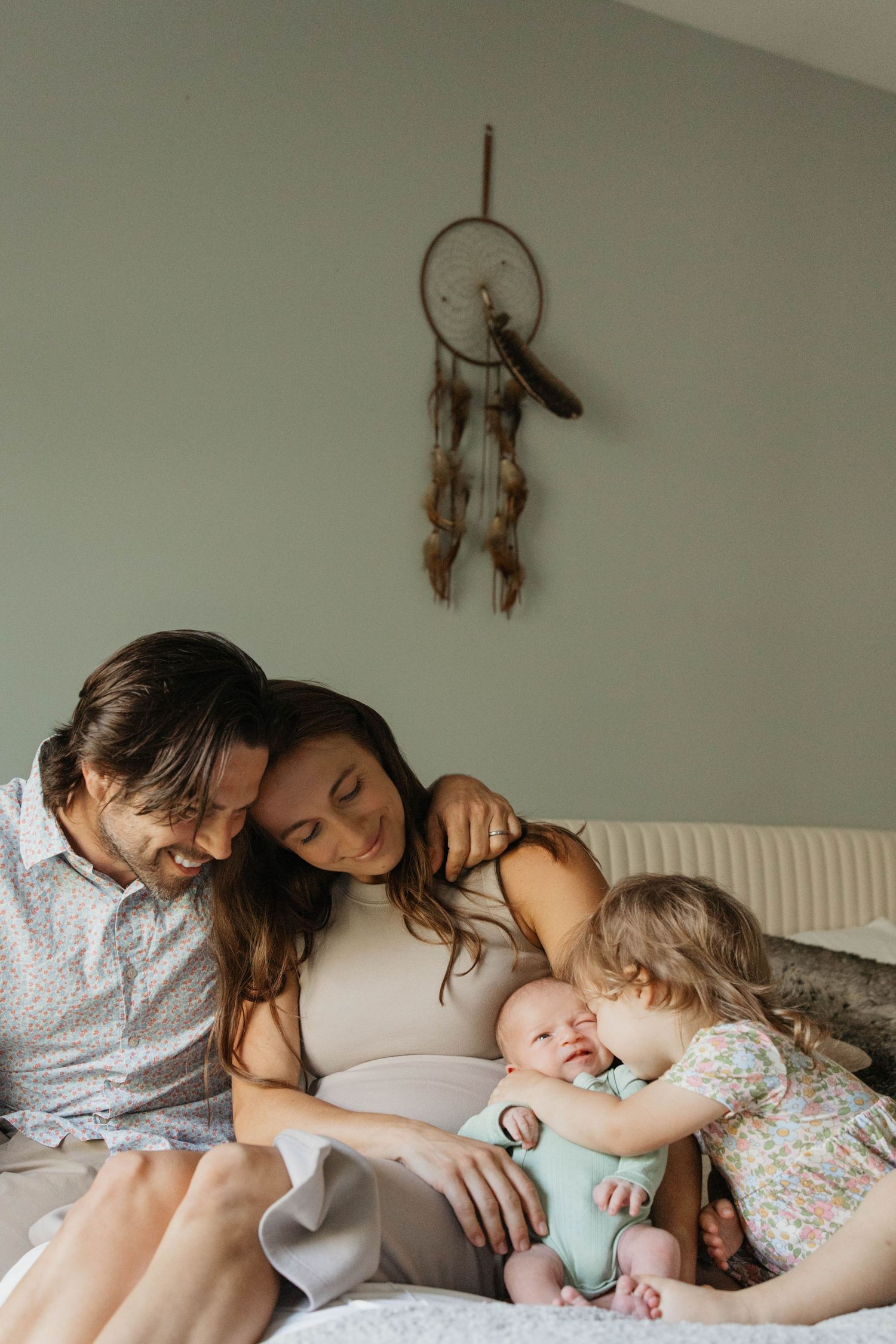 Family lying together on white bed sharing intimate moments of rest and connection.