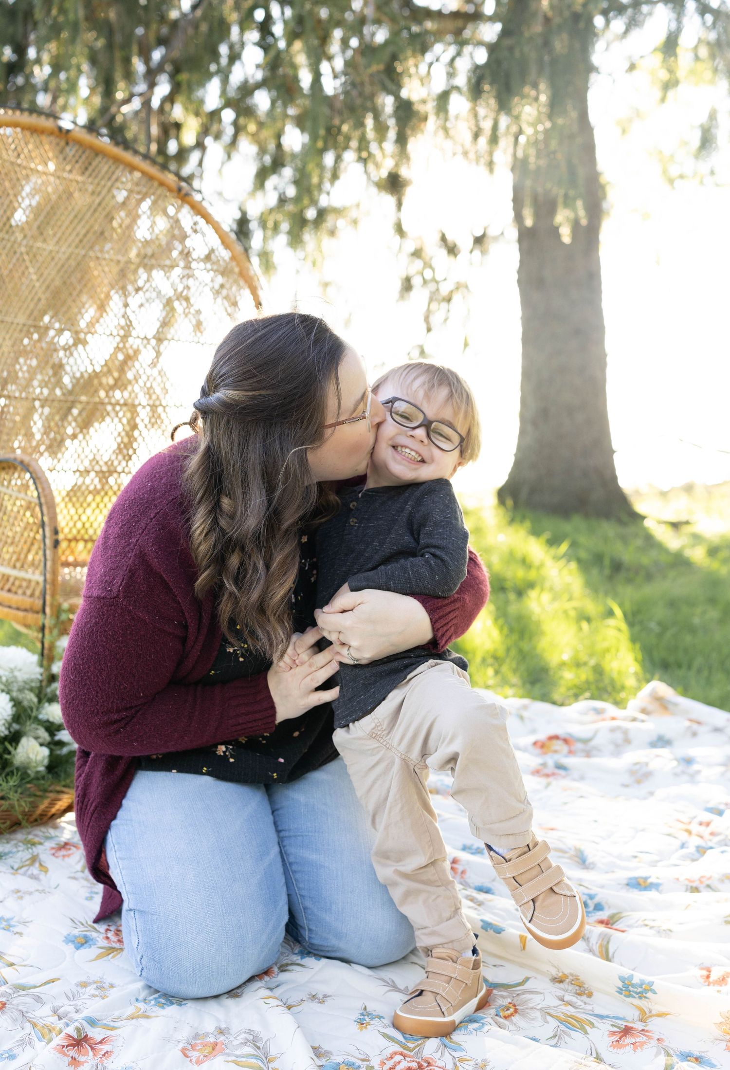 Loving moment shared on a picnic blanket outdoors with trees and sunlight in the background.