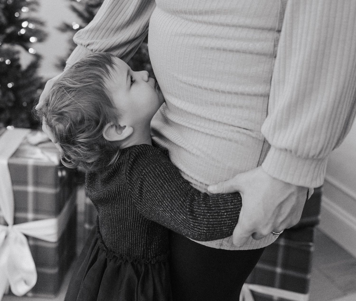 A couple in casual attire shares a tender moment while standing together in black and white photography.