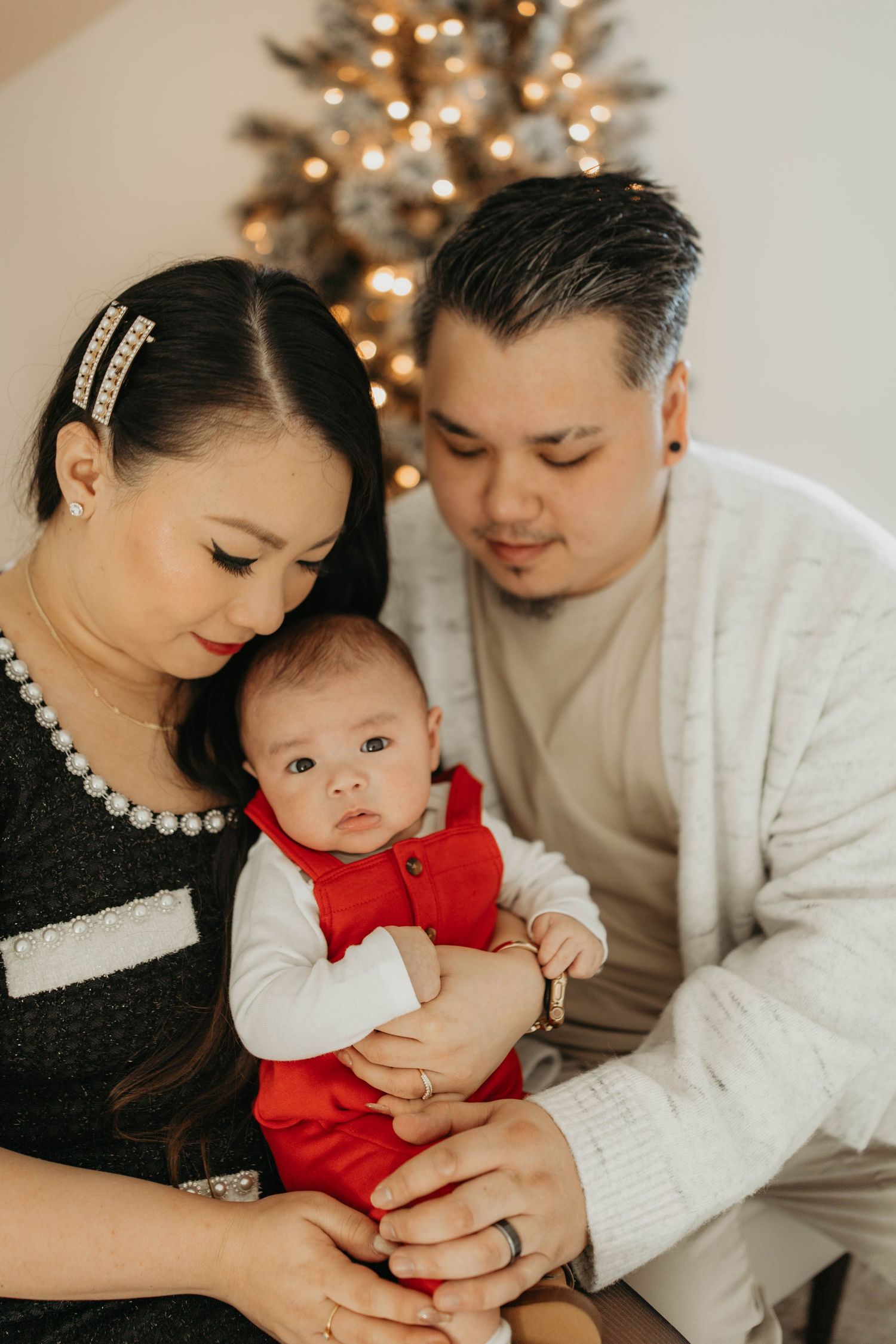 A cozy family holiday portrait in front of a Christmas tree with warm lighting and festive atmosphere.
