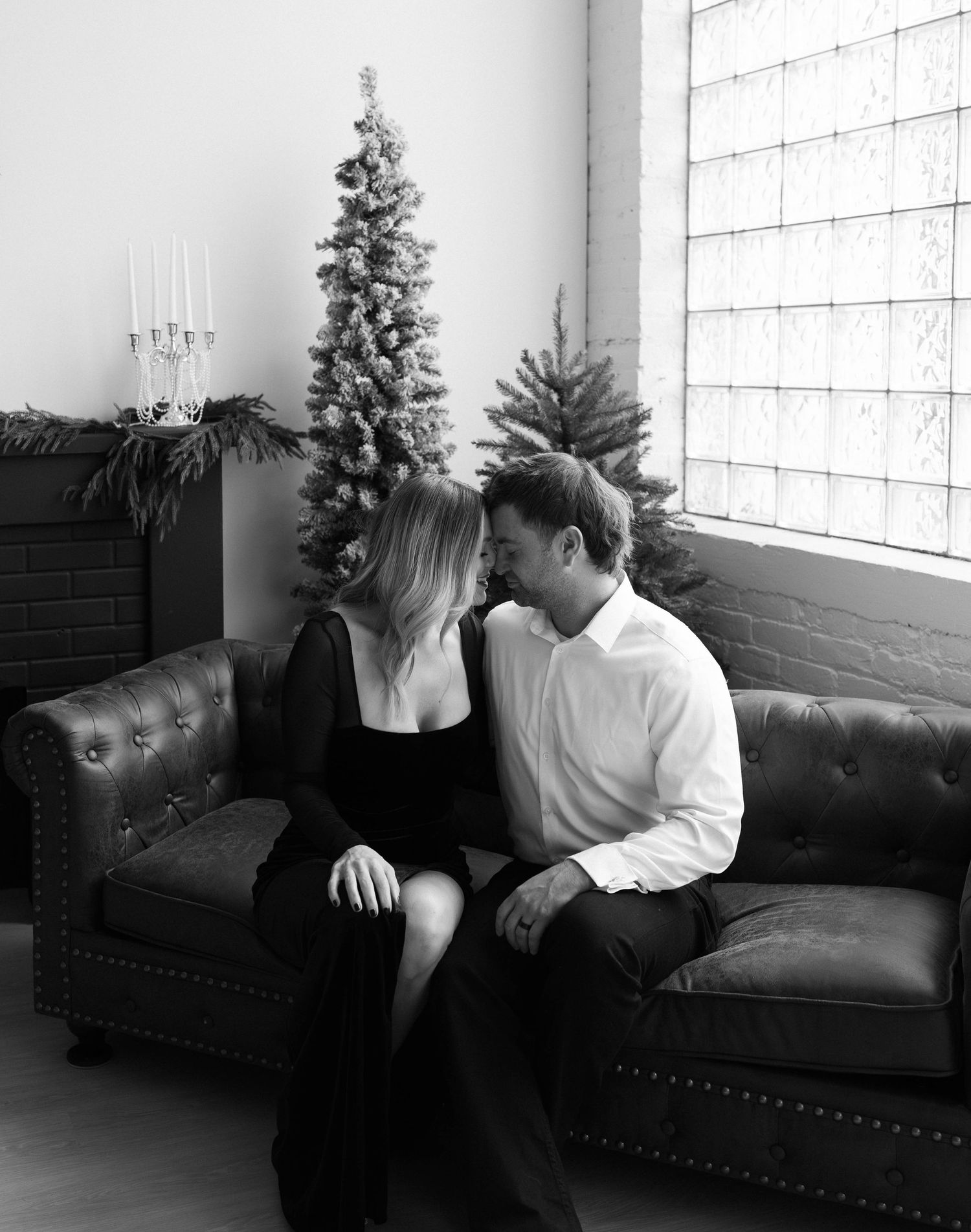 A romantic black and white holiday scene with a decorated Christmas tree and leather couch in an interior setting.