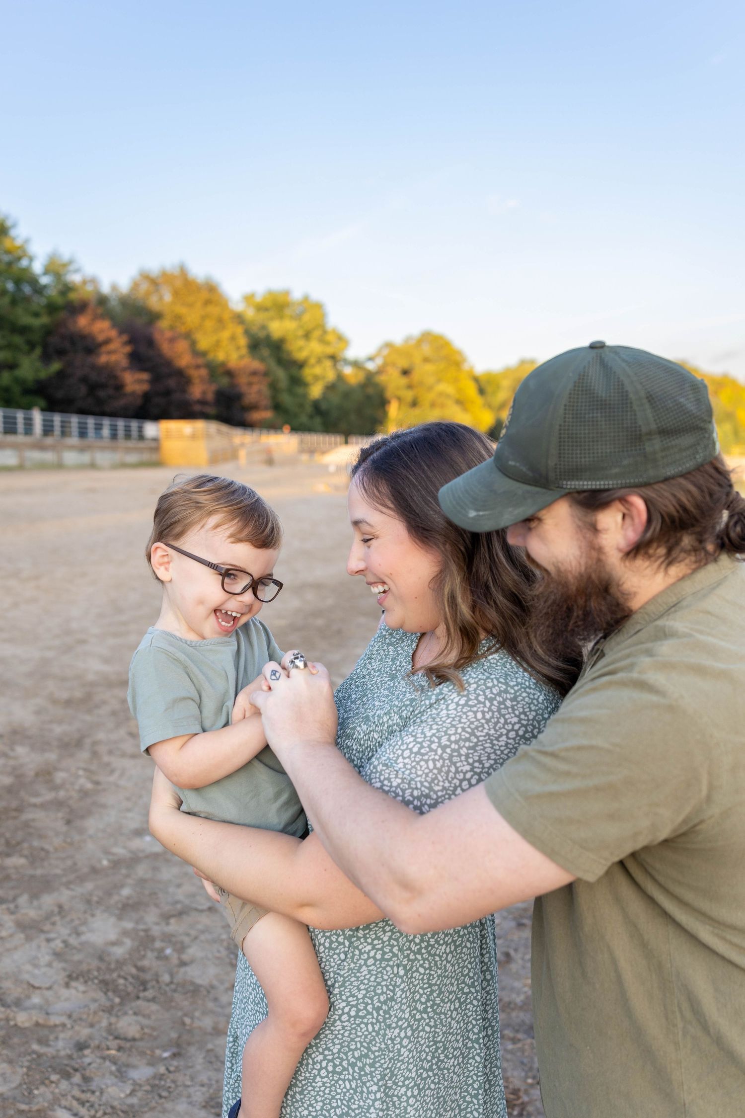 A family plays together with their small child on a sunny autumn day at a sandy beach location.