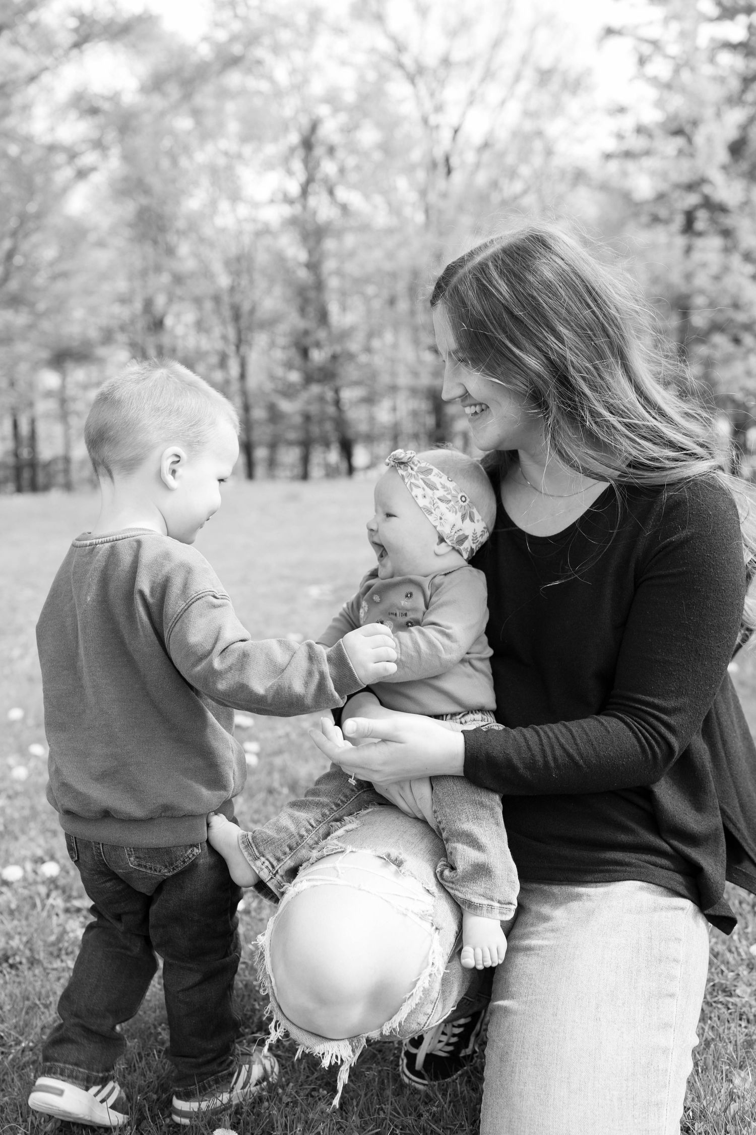 A tender black and white outdoor family moment as children and parent share time together with a balloon in a park.
