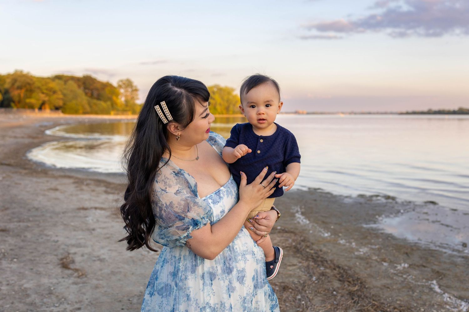 A scenic beachside photoshoot at sunset with warm golden light reflecting off the water and sand.