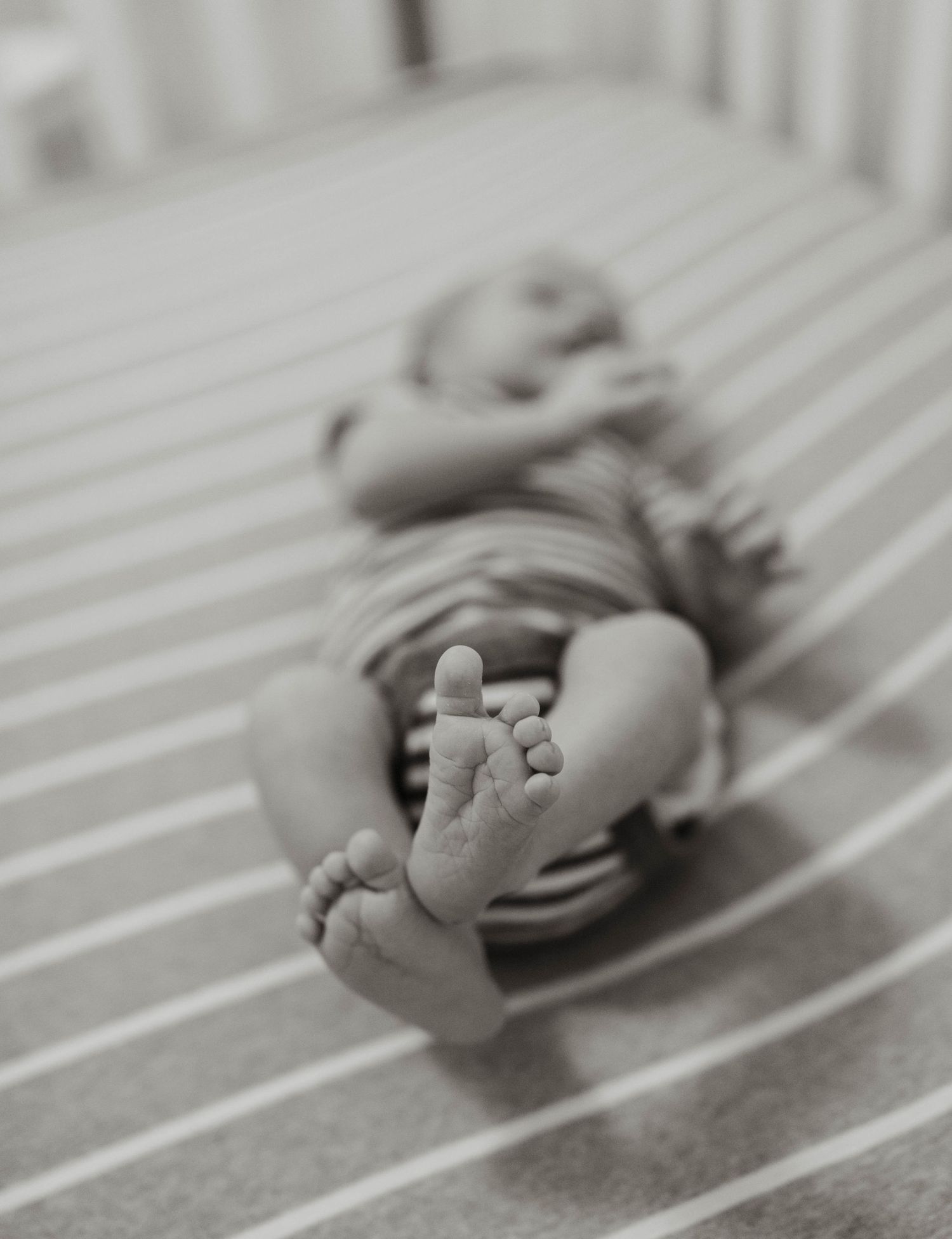 A sleeping newborn baby is shown in black and white through a progression of connected photographs.