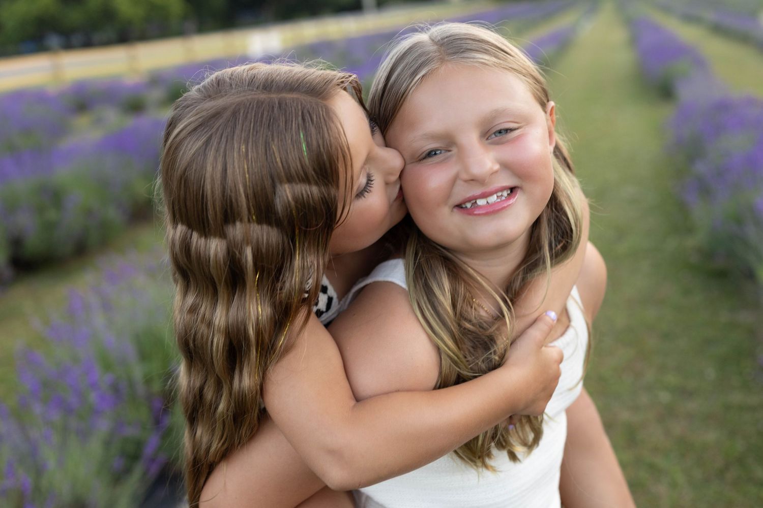 Two children share a sweet moment together in a lavender field on a sunny day.